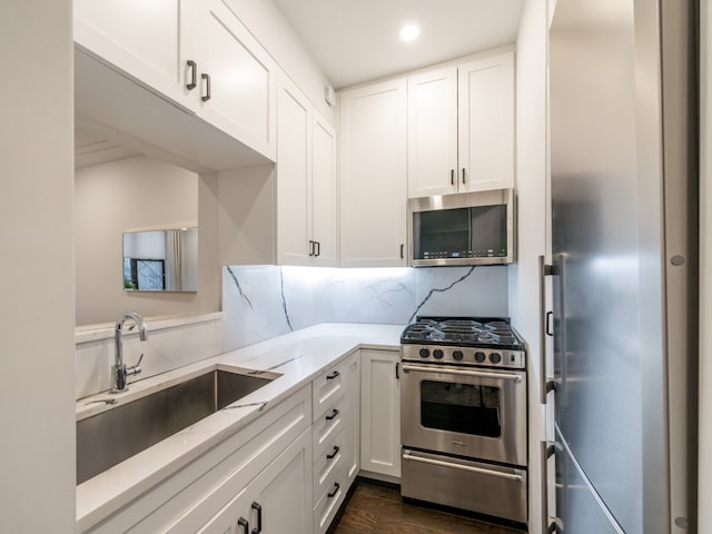kitchen featuring appliances with stainless steel finishes, a sink, light stone countertops, white cabinetry, and recessed lighting