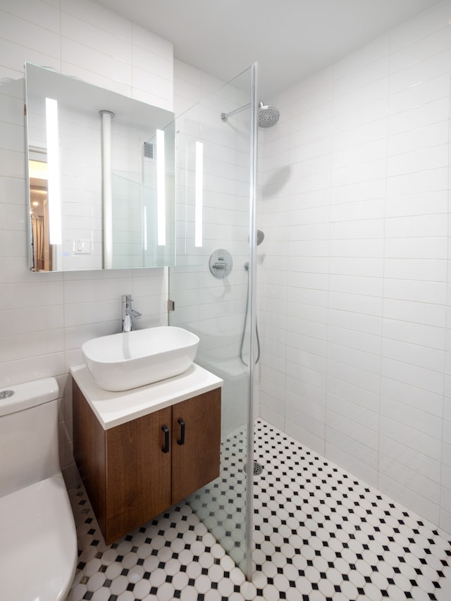full bath with a walk in shower, tile walls, toilet, and vanity