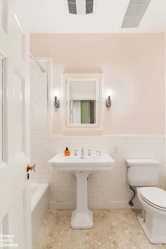 390 W End Ave Unit 5H, New York City, NY 10024 - full bathroom with toilet, tile walls, wainscoting, shower / bathtub combination, and tile patterned flooring