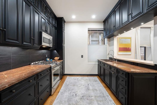 229 W 97th St Unit 1E, New York City, NY 10025 - kitchen featuring decorative backsplash, stainless steel range with gas stovetop, a sink, light wood-style floors, and dark cabinetry