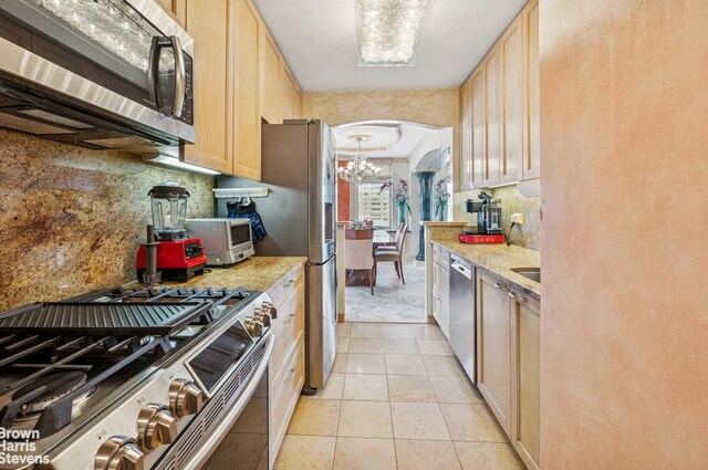 422 E 72nd St Unit 28D, New York City, NY 10021 - kitchen with appliances with stainless steel finishes, arched walkways, a chandelier, light tile patterned flooring, and decorative backsplash