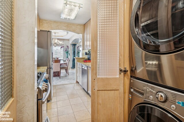 422 E 72nd St Unit 28D, New York City, NY 10021 - laundry room with estacked washer and dryer, light tile patterned flooring, and arched walkways