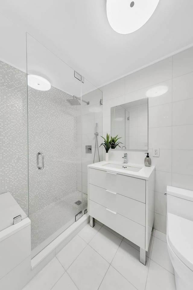 full bathroom featuring vanity, toilet, tile walls, tile patterned floors, and a shower stall