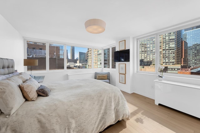 bedroom with baseboards, multiple windows, and wood finished floors