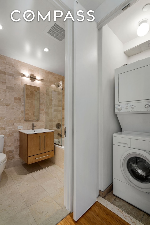 laundry area featuring recessed lighting, a sink, stacked washer and clothes dryer, and laundry area