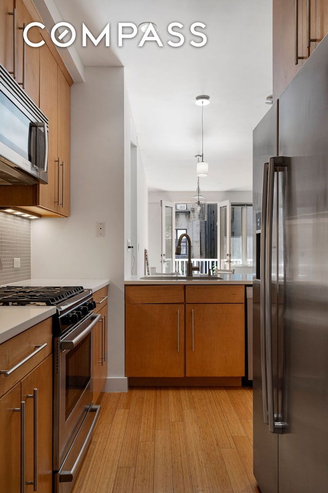 kitchen featuring appliances with stainless steel finishes, brown cabinetry, and light wood-style floors