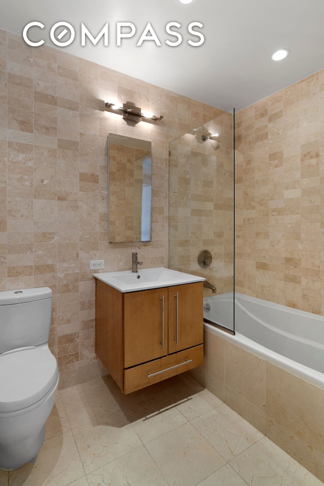 full bathroom featuring tiled shower / bath combo, toilet, recessed lighting, tile walls, and vanity