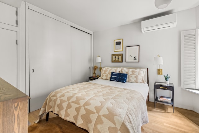 bedroom featuring a wall unit AC, a closet, and light wood finished floors