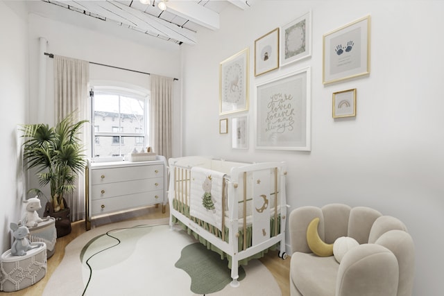 bedroom with wood finished floors, a nursery area, and beamed ceiling