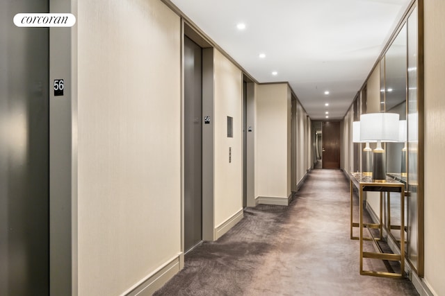 hallway featuring baseboards, dark colored carpet, recessed lighting, and elevator