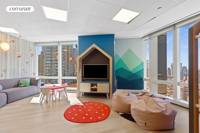 living area featuring expansive windows, wood finished floors, and a paneled ceiling
