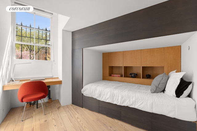 bedroom with light wood finished floors and an office area