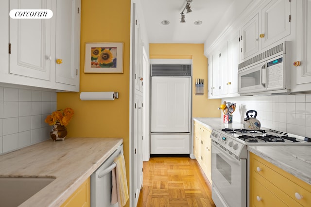 116 Pinehurst Ave Unit C15, New York City, NY 10033 - kitchen with white appliances, decorative backsplash, white cabinetry, and light stone countertops