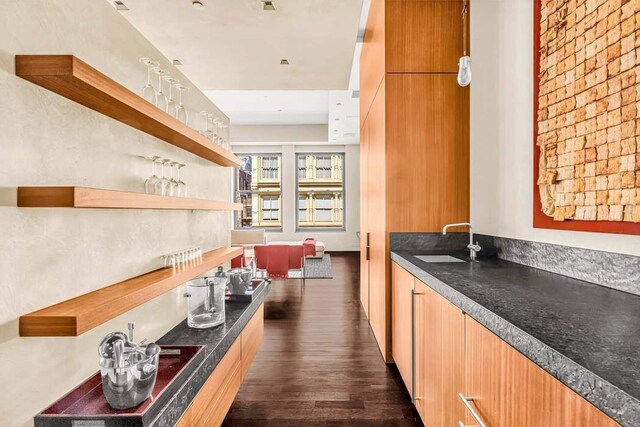 kitchen featuring open shelves, dark countertops, dark wood-style flooring, a sink, and modern cabinets