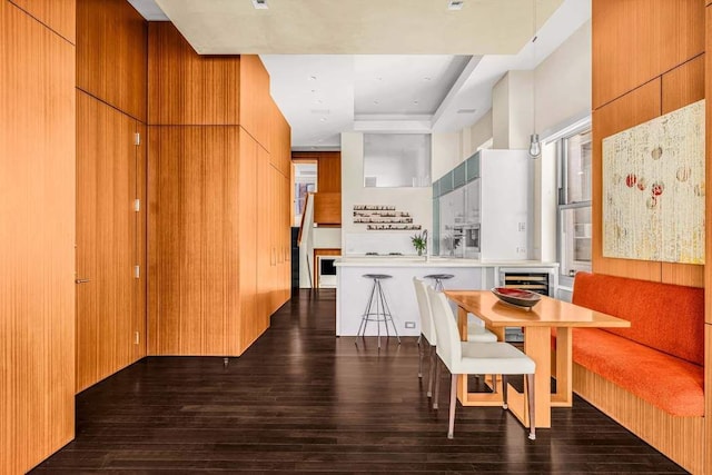 dining space featuring dark wood finished floors, a tray ceiling, and wine cooler