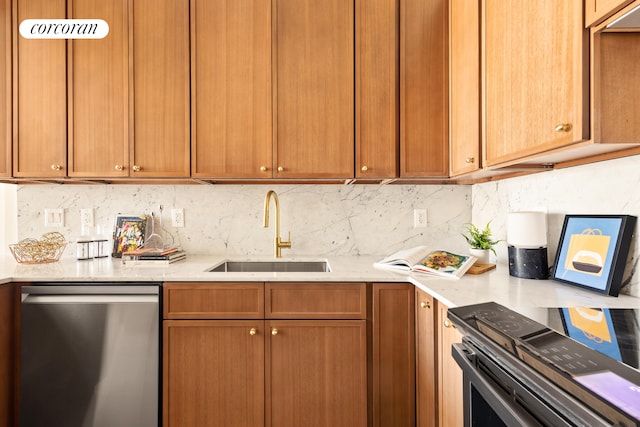 kitchen with appliances with stainless steel finishes, a sink, backsplash, light stone counters, and brown cabinets