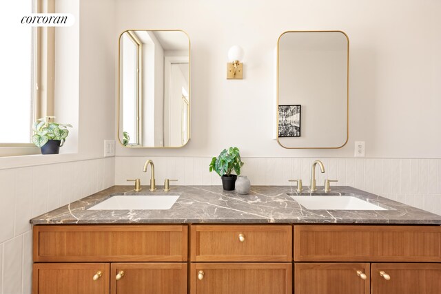 full bathroom featuring wainscoting and double vanity