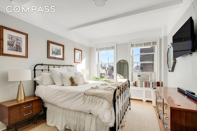 bedroom featuring light wood-type flooring, beam ceiling, and cooling unit