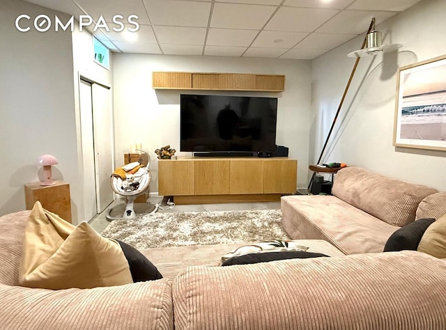 living room with a paneled ceiling and finished concrete flooring