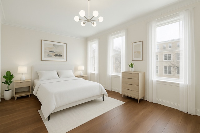 bedroom with hardwood / wood-style floors, crown molding, a chandelier, and baseboards