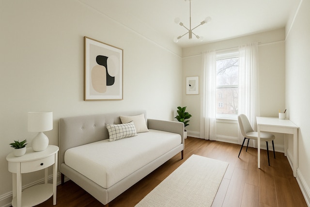 bedroom with wood finished floors, a chandelier, and baseboards