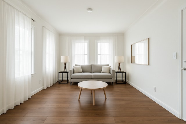 sitting room with baseboards, crown molding, and dark wood-type flooring