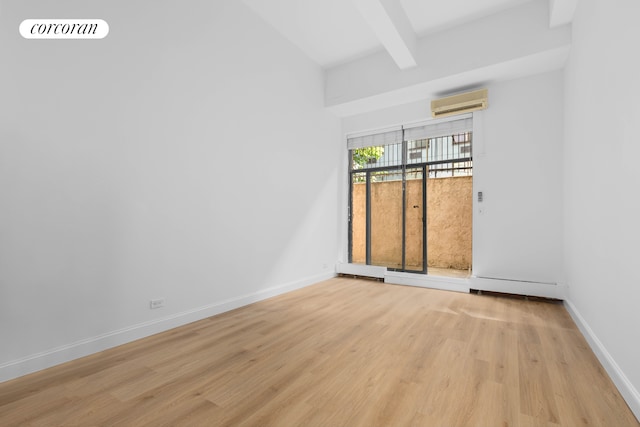 empty room with light wood-type flooring, beamed ceiling, an AC wall unit, and baseboards