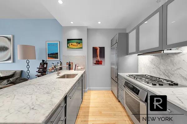 kitchen featuring appliances with stainless steel finishes, a sink, light wood-type flooring, light stone countertops, and gray cabinets
