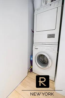 clothes washing area with stacked washing machine and dryer and light wood-style floors