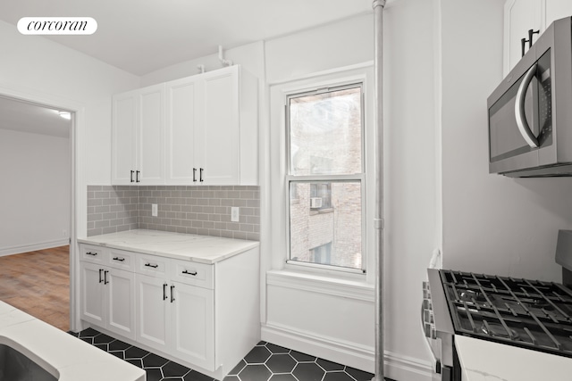 kitchen featuring appliances with stainless steel finishes, plenty of natural light, white cabinets, and tasteful backsplash