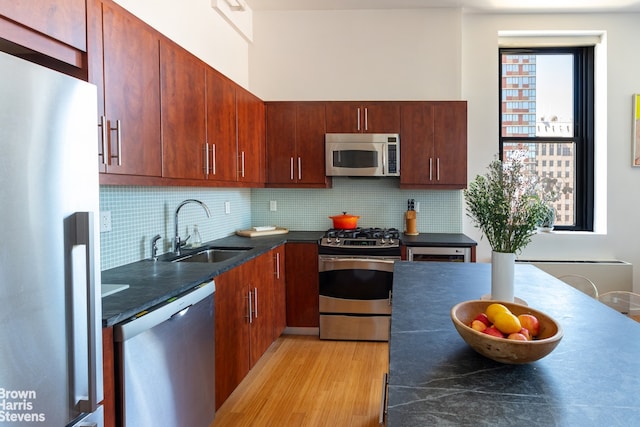 365 Bridge St Unit 23C, New York City, NY 11201 - kitchen featuring appliances with stainless steel finishes, a sink, dark countertops, light wood finished floors, and tasteful backsplash