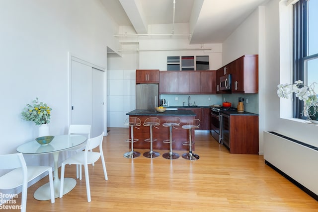 365 Bridge St Unit 23C, New York City, NY 11201 - kitchen with appliances with stainless steel finishes, dark countertops, a kitchen bar, a sink, and backsplash