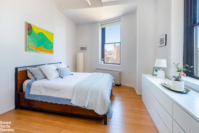 365 Bridge St Unit 23C, New York City, NY 11201 - bedroom with radiator, light wood-style floors, and baseboards