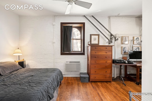 210 Spring St Unit 5, New York City, NY 10012 - bedroom with wood-type flooring, a ceiling fan, brick wall, and a wall mounted air conditioner