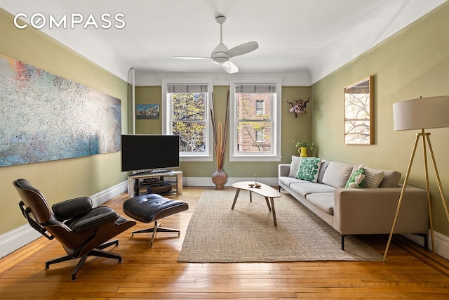 living area featuring ceiling fan, hardwood / wood-style flooring, and baseboards