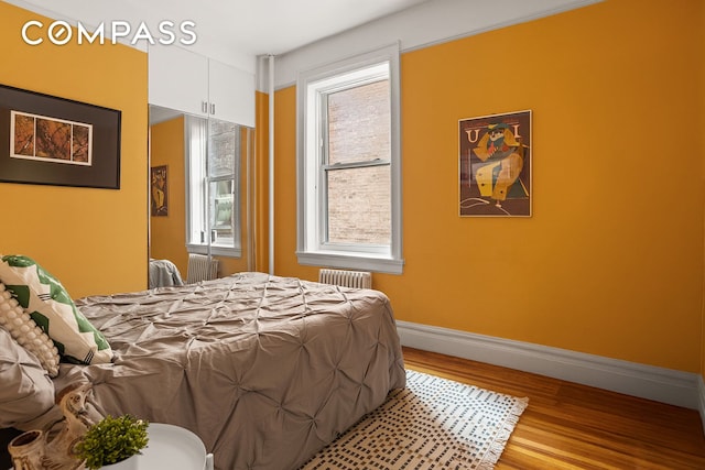 bedroom featuring radiator heating unit, wood finished floors, and baseboards