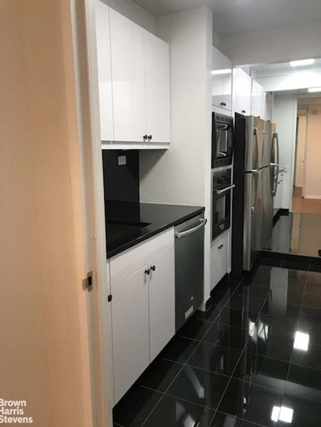 15 W 53rd St Unit 27E, New York City, NY 10019 - kitchen with appliances with stainless steel finishes, white cabinets, and tile counters