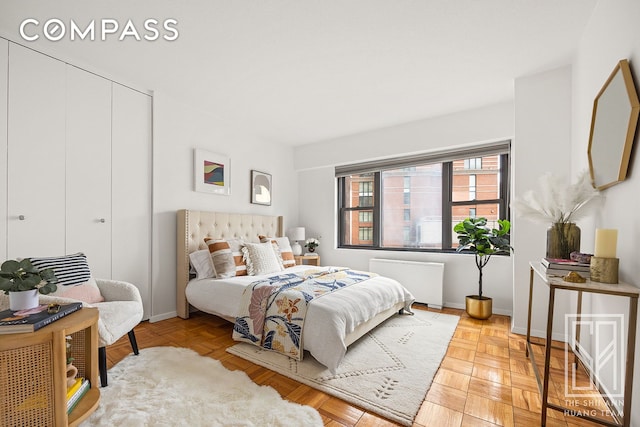bedroom with radiator heating unit, a closet, and baseboards