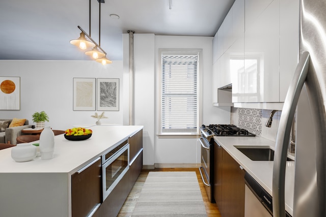 kitchen with modern cabinets, stainless steel appliances, light countertops, and backsplash