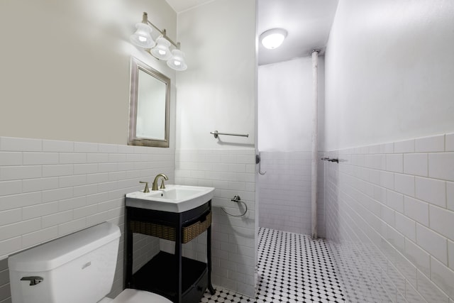 full bath with tile walls, a wainscoted wall, tiled shower, toilet, and tile patterned flooring