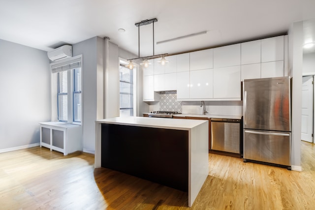 kitchen featuring stainless steel appliances, a wall mounted air conditioner, modern cabinets, a sink, and light countertops