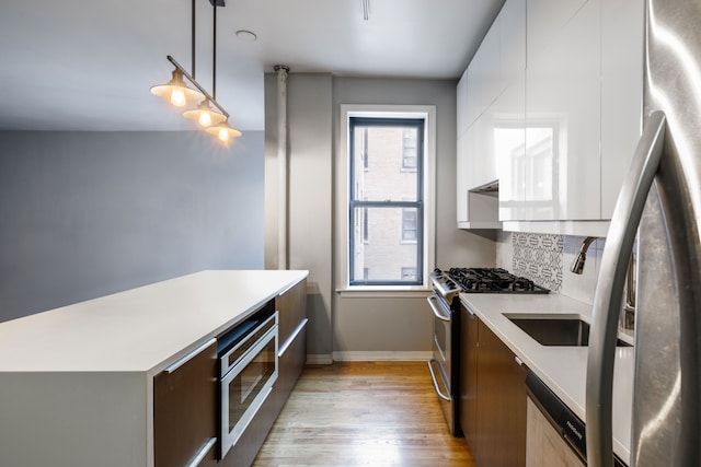 kitchen with modern cabinets, appliances with stainless steel finishes, light countertops, and light wood-style floors