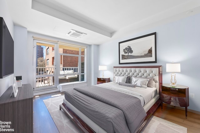 bedroom featuring wood finished floors, access to outside, and baseboards