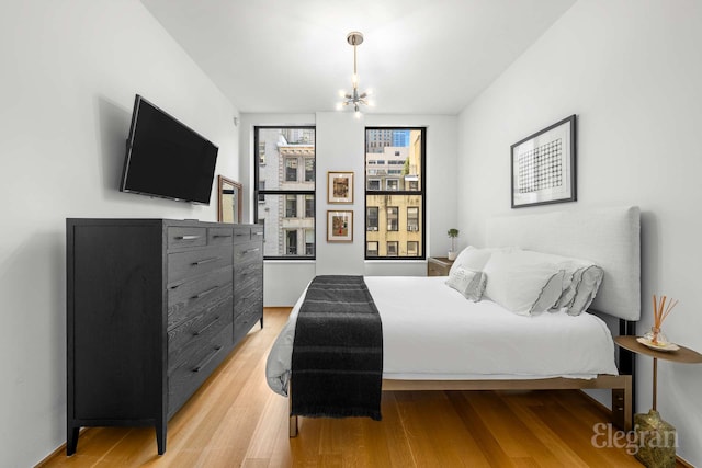 bedroom with light wood-style floors and a chandelier