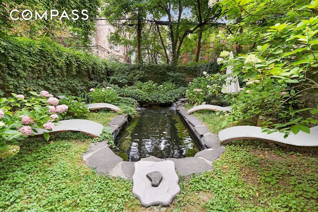 view of property's community featuring a garden pond