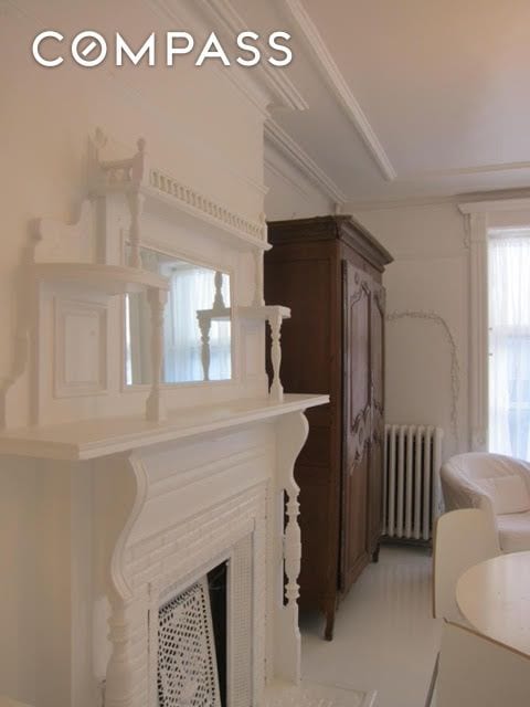 room details featuring crown molding, radiator, and a fireplace