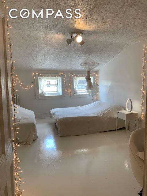 bedroom with concrete floors and a textured ceiling
