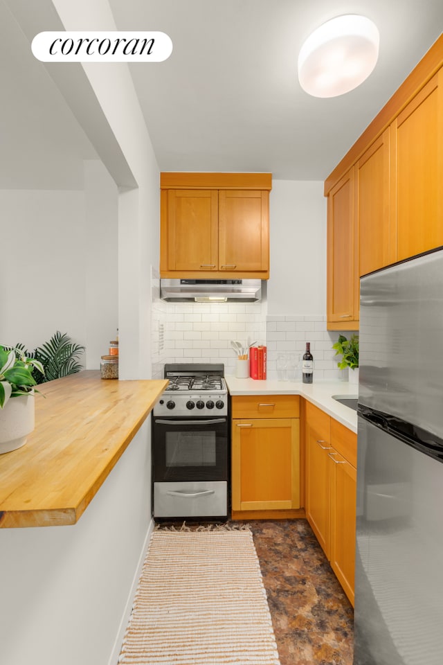 350 Bleecker St Unit 2K, New York City, NY 10014 - kitchen featuring appliances with stainless steel finishes, under cabinet range hood, decorative backsplash, a peninsula, and wood counters