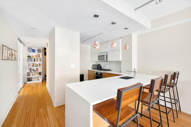 303 E 33rd St Unit 7C, New York City, NY 10016 - kitchen with modern cabinets, a kitchen bar, light countertops, a peninsula, and a sink