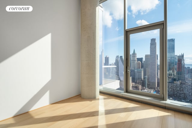 56 Leonard St Unit 44Be, New York City, NY 10013 - empty room featuring a skyline view, wood finished floors, plenty of natural light, and a wall of windows